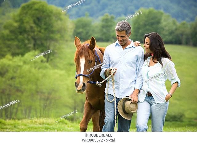 man and a woman walking with a horse