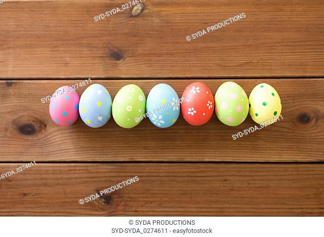 row of colored easter eggs on wooden table