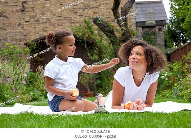 Mother and daughter eating in backyard