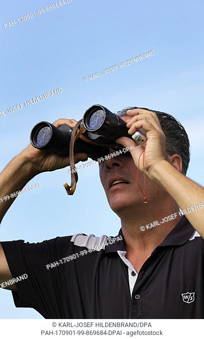 Paragliding teacher Harti Waitl watches a pupil with a pair of binoculars at his school near Schwangau, Germany, 30 July 2017