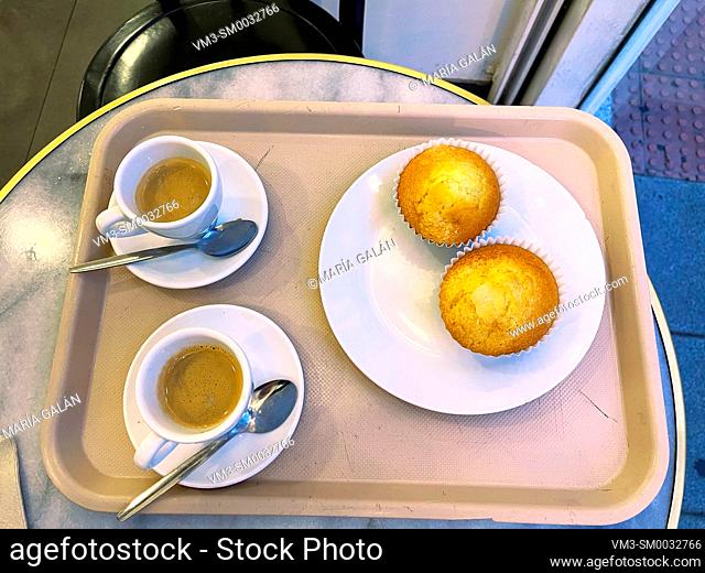 Two cups of coffee with muffins on a tray. View from above