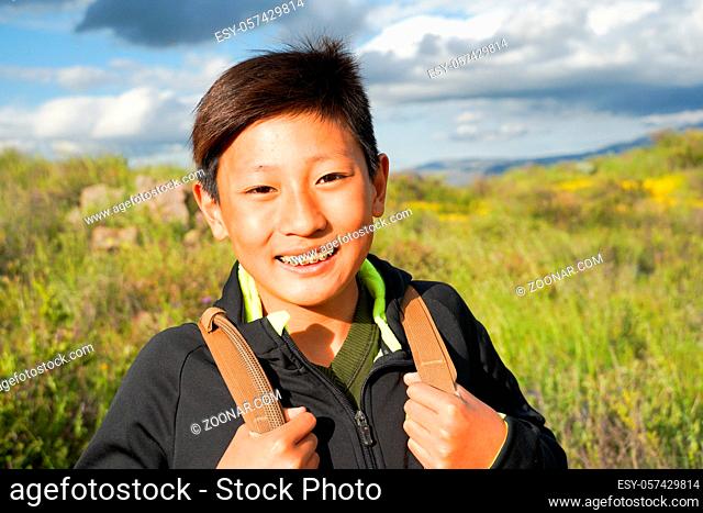Young sporty Asian boy enjoying and hiking the mountain during the California Golden Poppy and Goldfields blooming in Walker Canyon, California. USA