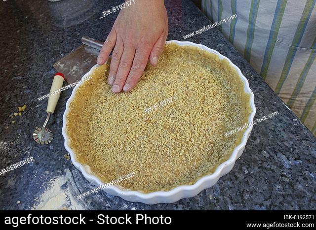 Southern German cuisine, baking, preparation of hearty vegetable cake with walnut base, walnut dough in the baking tin, tart tin, quiche tin, pastry wheel