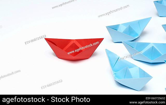 group of paper boats on a white background. concept of a strong leader in a team, manipulation of the masses, following new perspectives