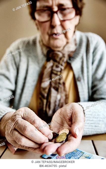 Senior citizen sits at the table and counts her money, Germany