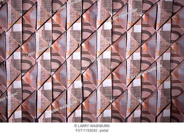 Ten Euro banknotes folded into diamond shapes and interwoven, full frame