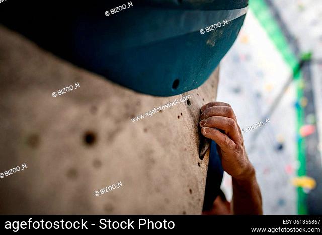 Close up shot of a male hand smeared with magnesium powder grabbing a hold of a climbing wall, at the gym