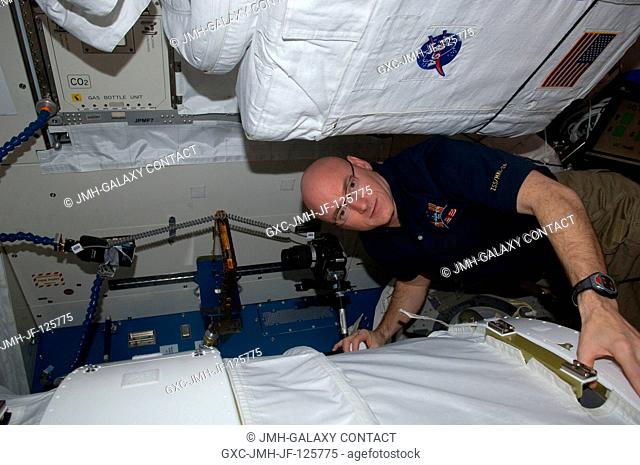 NASA astronaut Scott Kelly, Expedition 26 commander, uses a digital still camera to photograph the Binary Colloidal Alloy Test-5 (BCAT-5) payload setup in the...