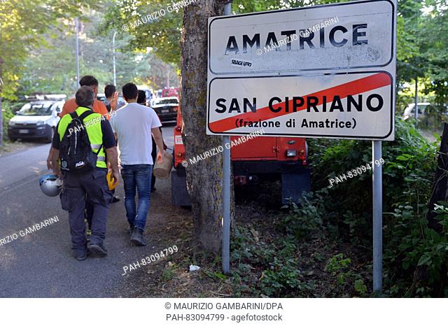 Rescue workers walk past a town sign in Amatrice, Italy, 25 August 2016. A strong earthquake claimed numerous lives in central Italy on 24 August 2016