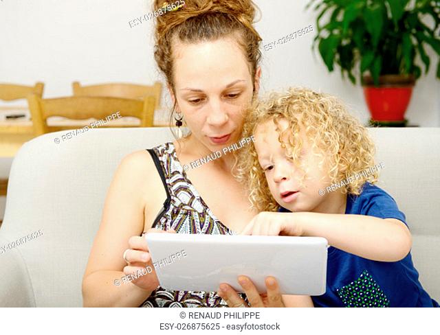 a blond child and her mom uses a digital tablet