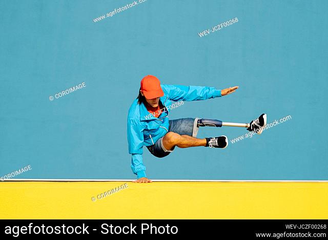 Young disabled man doing handstand against multi colored wall