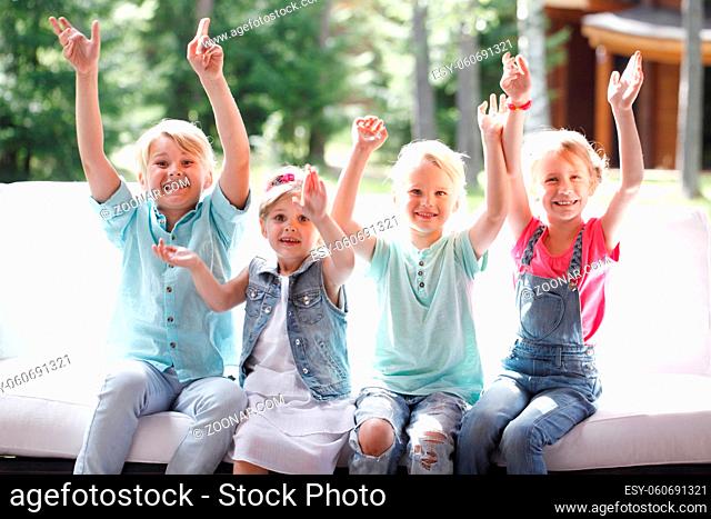 Image of happy children friends raising arms and screaming in joy