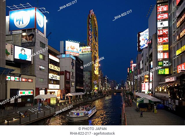 Tour boat on Dotonbori River glides past shops and restaurants in Namba, Osaka, Japan, Asia