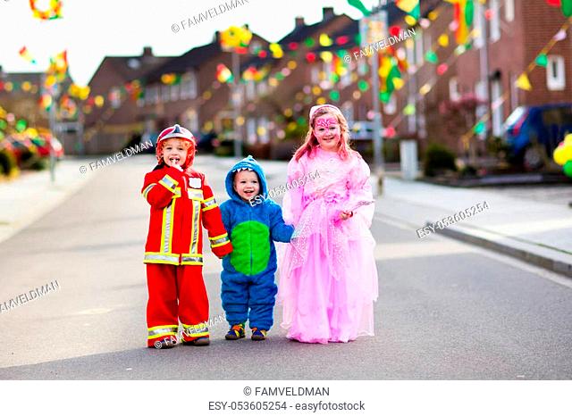 Kids on Halloween trick or treat. Children in Halloween costumes with candy bags walking in decorated city neighborhood trick or treating