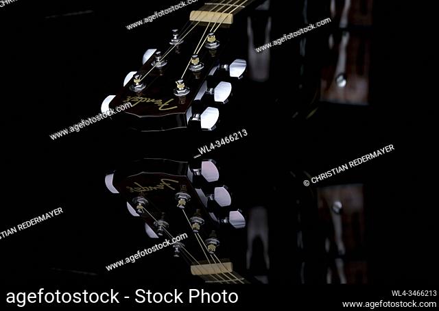 Close up image form a classic guitar on a mirror as background painted with light