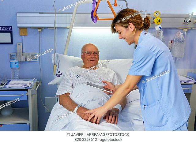 Nurse with tablet attending to patient, hospital room, Hospital Donostia, San Sebastian, Gipuzkoa, Basque Country, Spain