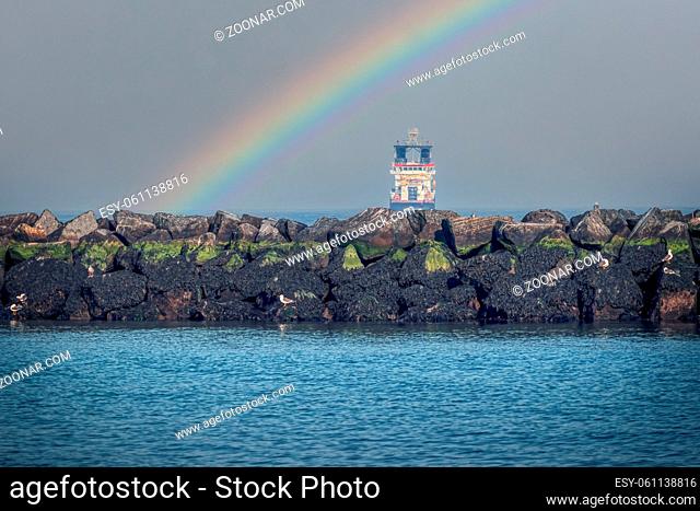 Large ship just off the coast of Dune. Seagulls on the rocks in the foreground. with a rainbow. Focus on rocks