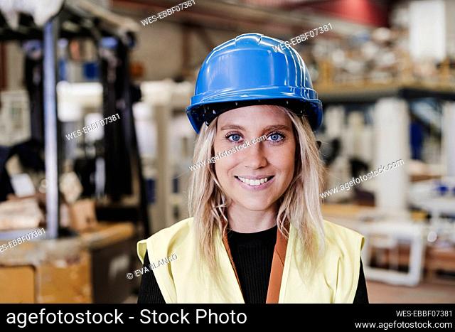 Happy young engineer wearing hardhat standing in industry