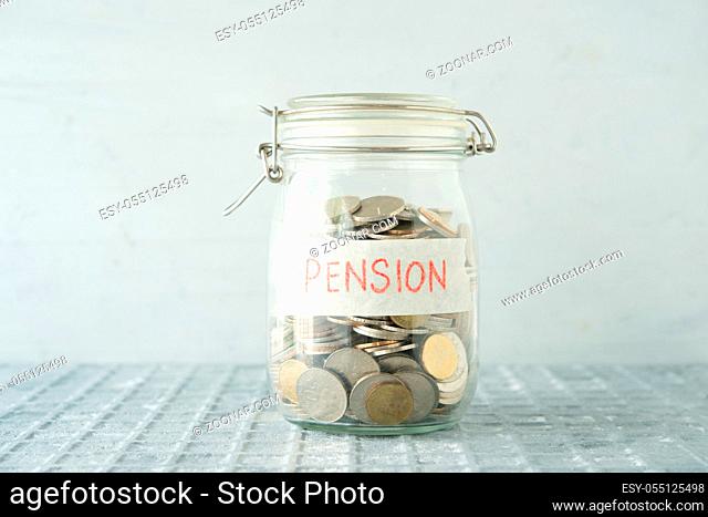 Coins in glass money jar with pension label, financial concept