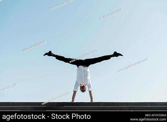 Businessman doing a handstand on top of stairs