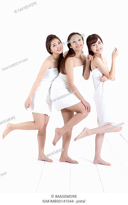 Three young women standing on one foot against each other smiling happily