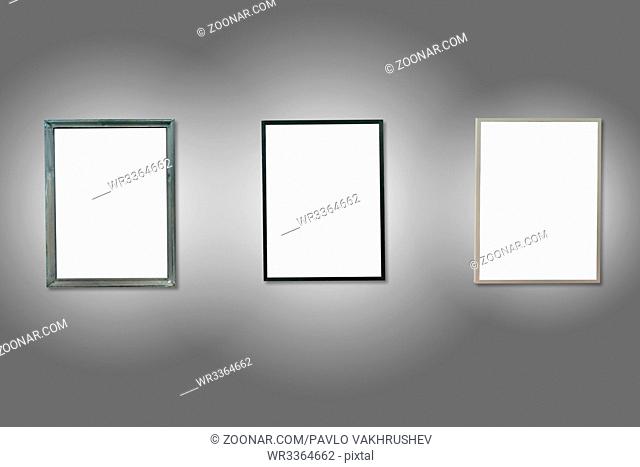 Three white isolated wooden frames on the gray wall