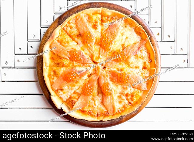 Pizza with smoked salmon and egg on white wooden table