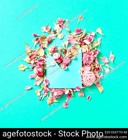Congratulation composition of handmade envelope and pink roses flowers on a light turquoise background with copy space. Flat lay