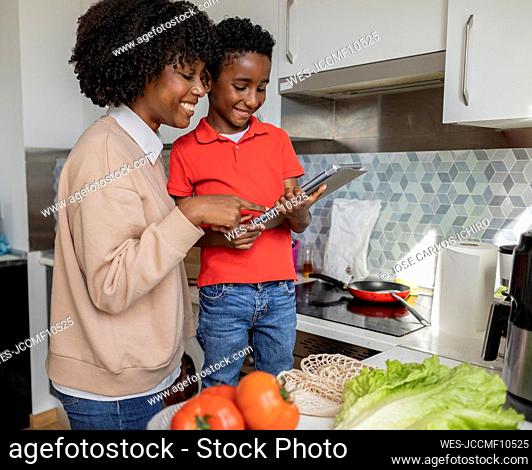 Happy mother and son using tablet PC in kitchen at home