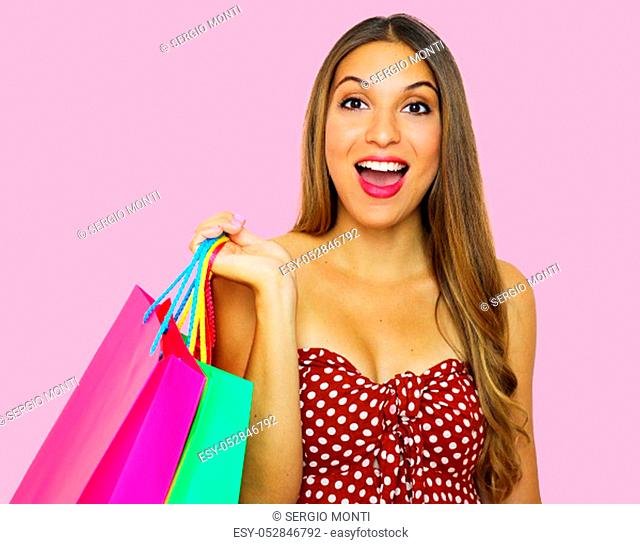 Excited fashion woman holding shopping bags on pink background