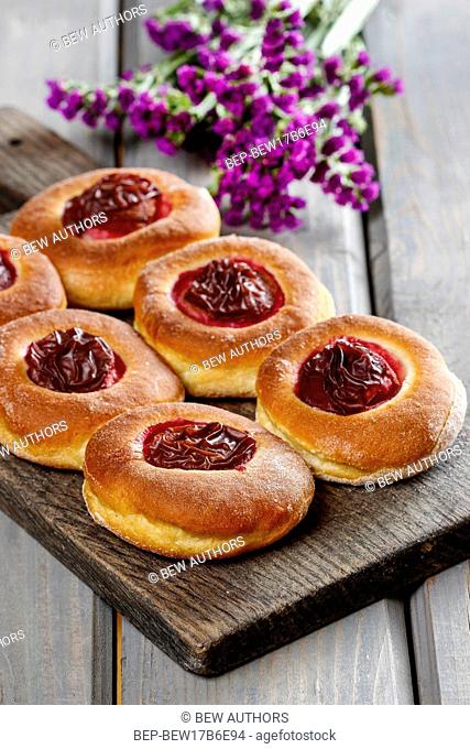 Round buns with plum on wooden table