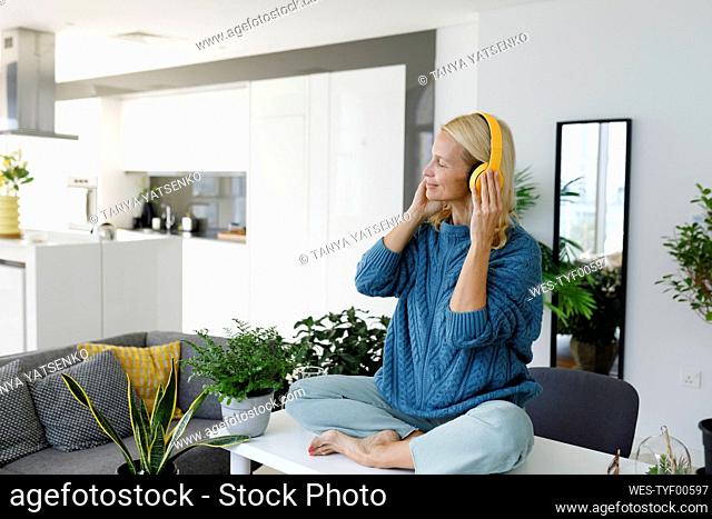 Woman wearing wireless headphones listening to music at home