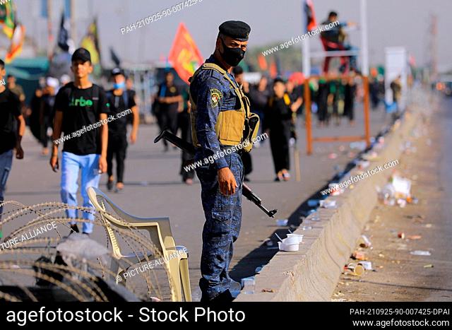25 September 2021, Iraq, Baghdad: A member of the Iraqi security forces (R) observes Shia Muslims march from Baghdad to visit the the Husayn Mosque in Karbala...
