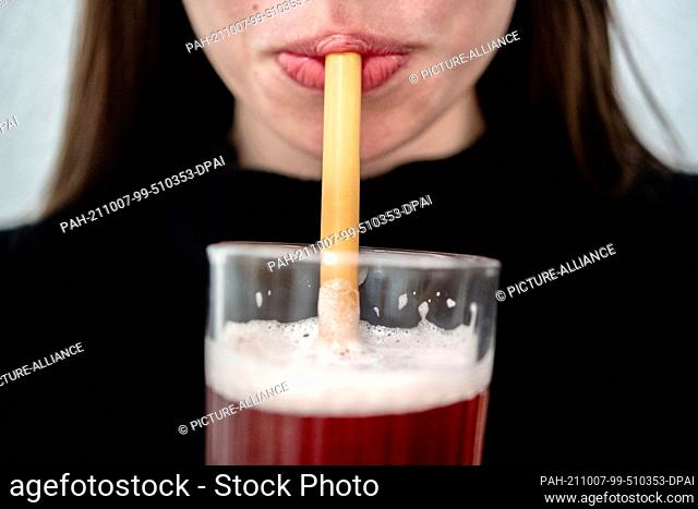 PRODUCTION - 06 October 2021, Lower Saxony, Hanover: A young woman drinks from a glass through a bamboo drinking straw. (to dpa ""Three months of other drinking...