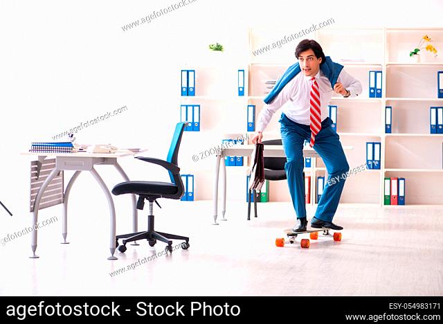 Young handsome businessman with longboard in the office