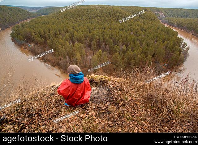 Male hiker sitting the hilltop watching to the river, top view