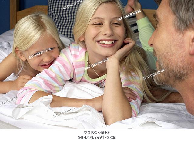 Father at the bed of his two blond daughters, close-up