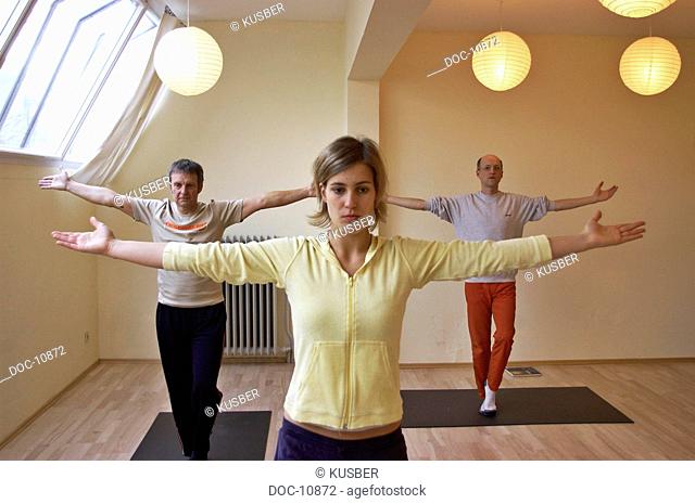 Two men and a woman with arms Outstretched doing yoga