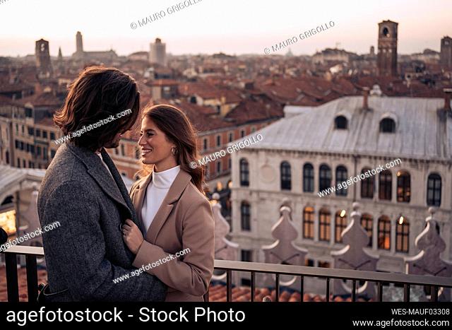 Happy young couple on a balcony above the city of Venice, Italy