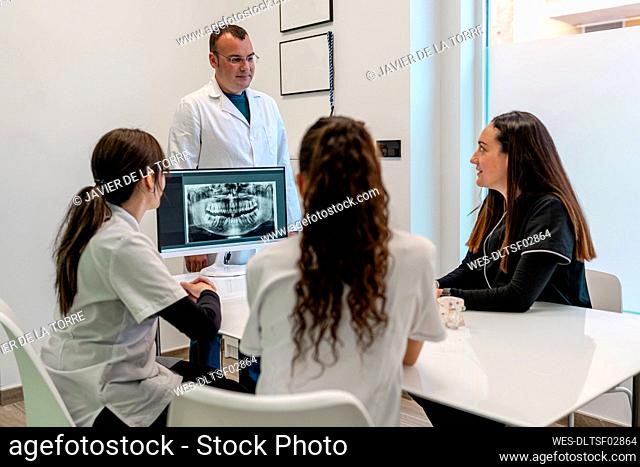 Dentist and nurses discussing over medical x-ray in hospital