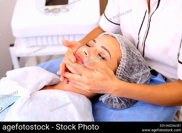 Beautician makes cleansing and exfoliating facial for beautiful girl. Beauty salon