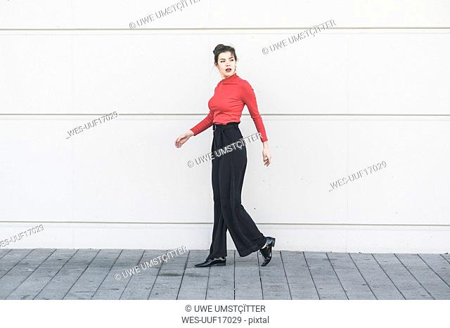 Elegant young walking along a wall