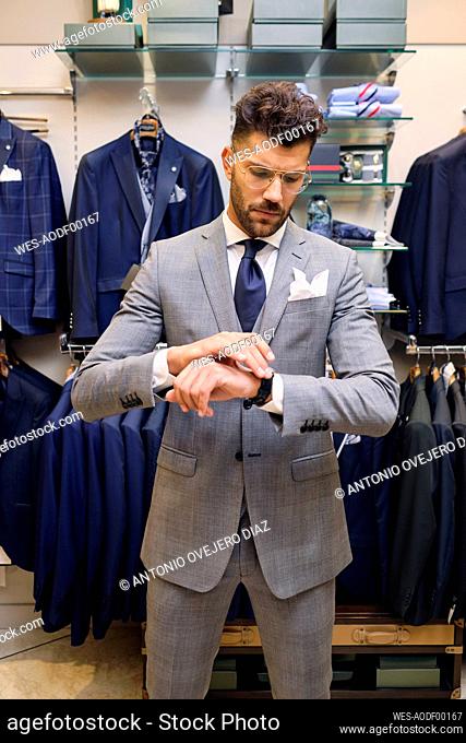 Man in gray suit checking time in tailors boutique