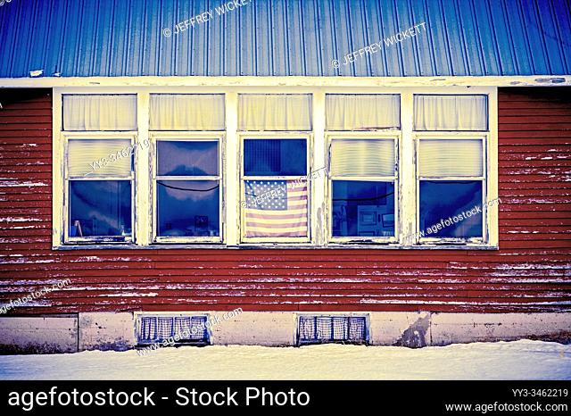 American flag hanging in the window of an old abandoned school house in the UP of Michigan