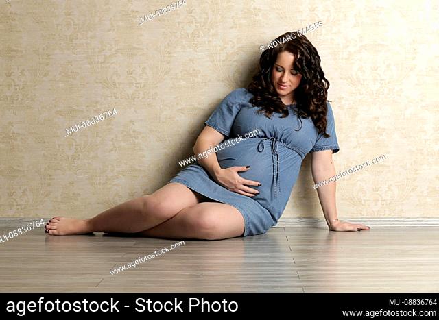 Pregnant woman is sitting on floor