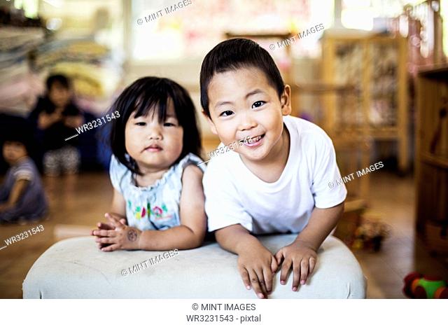 Smiling boy and girl in a Japanese preschool, looking at camera