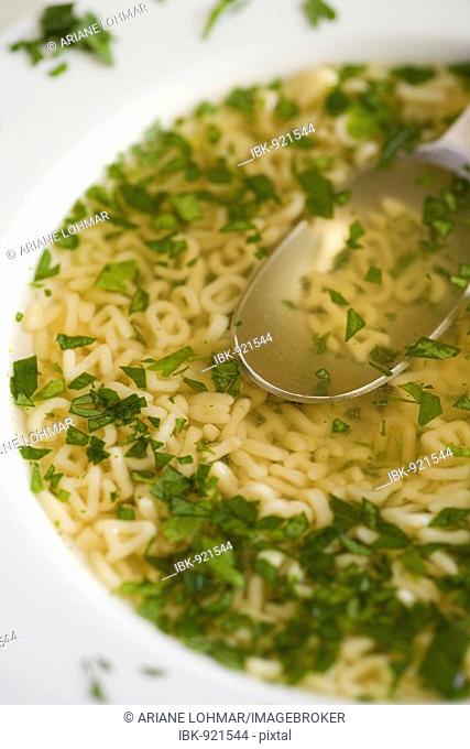 Alphabet soup with parsley and noodle letters, spoon