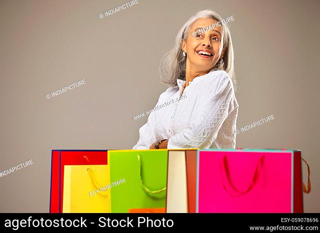 An old woman smiling behind her Carrybags