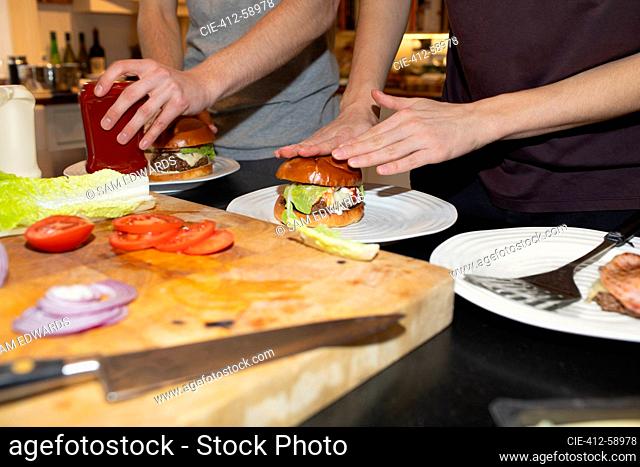 Teenage boys assembling hamburgers in kitchen