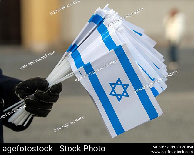 26 November 2023, Bavaria, Munich: A participant holds a bundle of Israeli flags at a rally for Israel on Odeonsplatz. Several hundred people showed their...